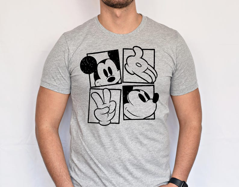 May include: A gray t-shirt featuring a black and white graphic of Mickey Mouse. The design is divided into four squares, each showcasing a different element of Mickey's iconic features: his face, hand, and peace sign.