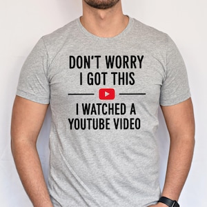Pode incluir: Uma camiseta cinza com o texto "Don't worry I got this I watched a YouTube video" e um &iacute;cone de bot&atilde;o de reprodu&ccedil;&atilde;o do YouTube vermelho.