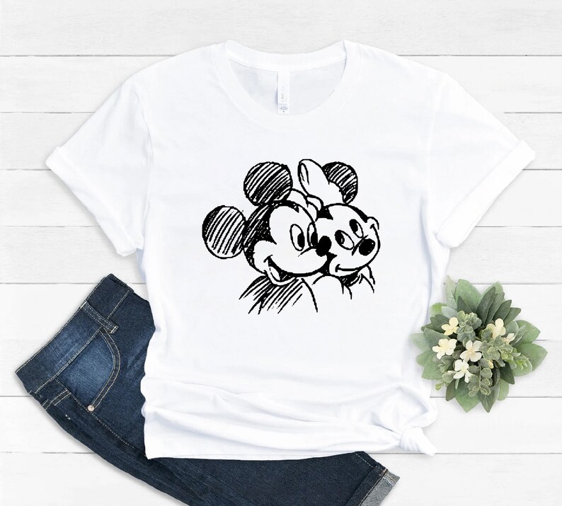 May include: White t-shirt with a black and white sketch of Mickey Mouse and Minnie Mouse.