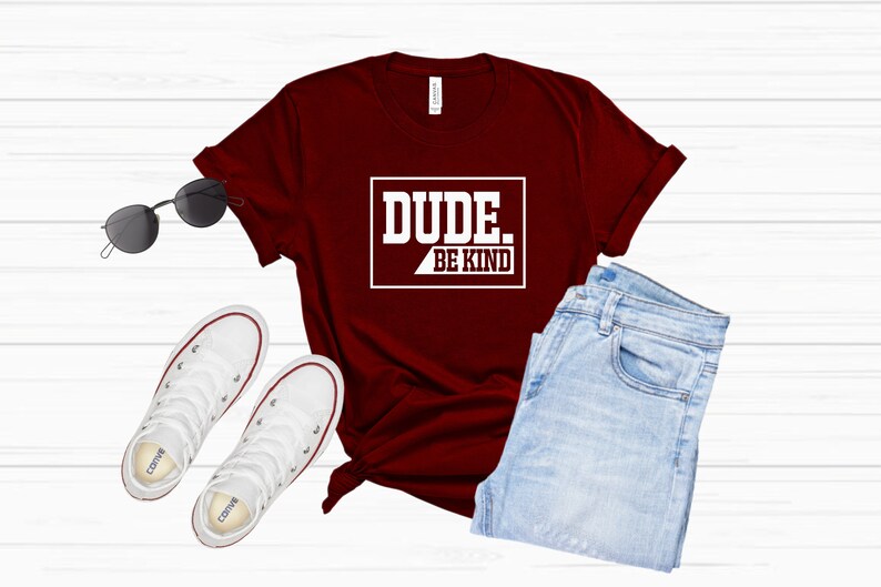 May include: A maroon t-shirt with white text that reads "DUDE. BE KIND" in a rectangular box.