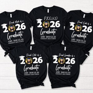 May include: Black t-shirts with white text and a photo of a graduate. The shirts read "Proud Mom of a 2026 Graduate," "P.R.O.U.D 2026 Graduate," "Proud Dad of a 2026 Graduate," "Proud Sister of a 2026 Graduate," and "Proud Grandpa of a 2026 Graduate."