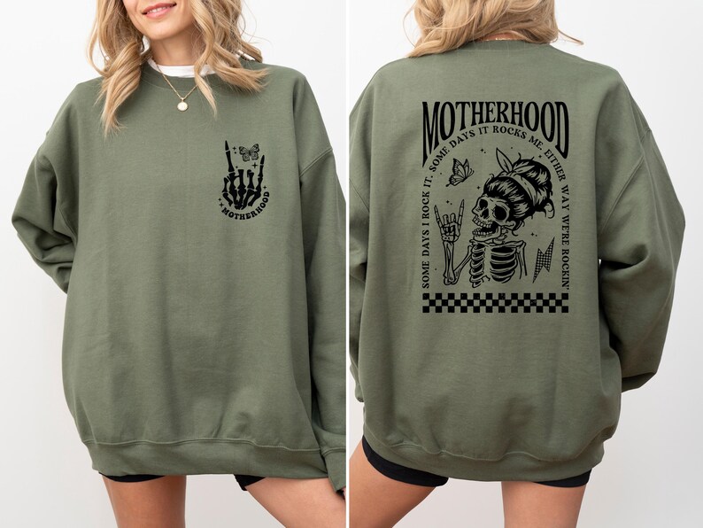 May include: Green sweatshirt with a black graphic print of a skeleton with a butterfly and the text "MOTHERHOOD. SOME DAYS I ROCK IT. SOME DAYS IT ROCKS ME. EITHER WAY WE'RE ROCKIN'" on the back. The front of the sweatshirt has a smaller graphic print of a skeleton hand with a butterfly and the text "MOTHERHOOD".