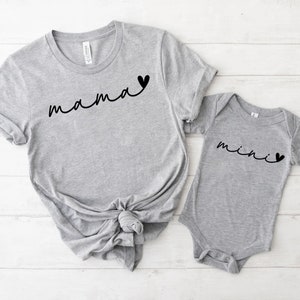 May include: Gray t-shirt with the word "mama" and a small heart, and a gray baby onesie with the word "mini" and a small heart.