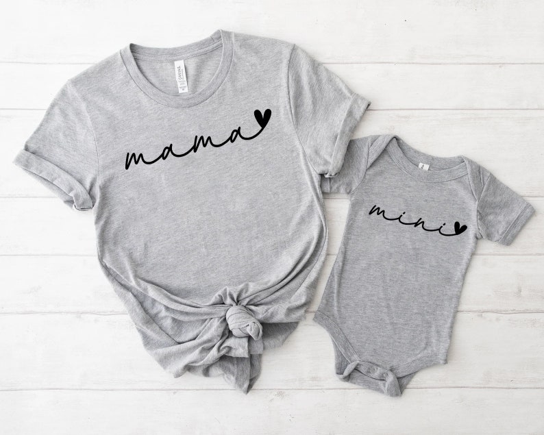 May include: Gray t-shirt with the word "mama" and a small heart, and a gray baby onesie with the word "mini" and a small heart.