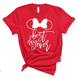May include: Red t-shirt with a white bow and the text "best day ever" in white.