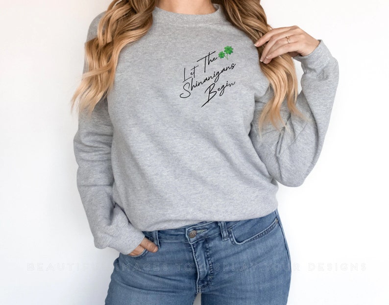 Peut inclure: Un sweat-shirt gris avec le texte "Let the Shenanigans Begin" en &eacute;criture noire avec des tr&egrave;fles verts.