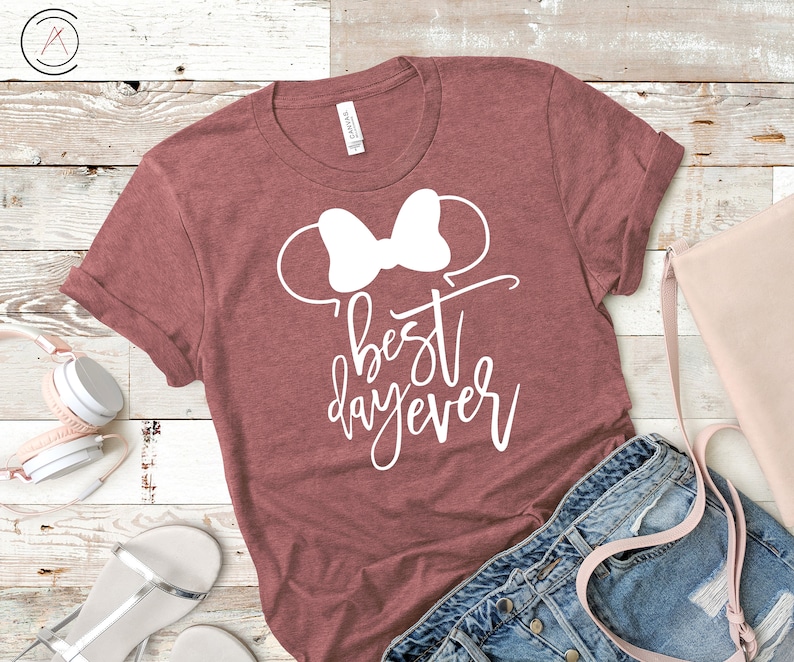 May include: A maroon t-shirt with a white bow and the text "best day ever" in white cursive writing.