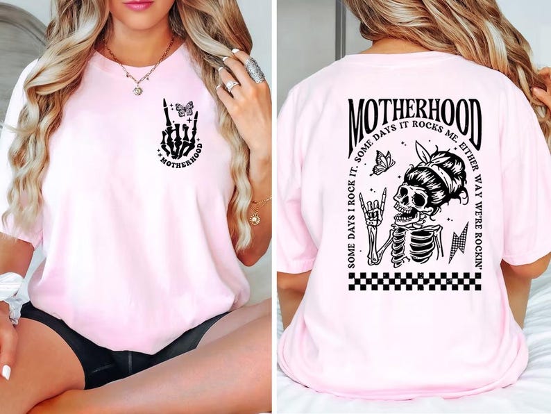 May include: Pink t-shirt with a black skeleton graphic and the text "MOTHERHOOD SOME DAYS I ROCK IT. SOME DAYS IT ROCKS ME. EITHER WAY WE'RE ROCKIN'" on the back. The front of the shirt has a black skeleton hand graphic with a butterfly and the text "MOTHERHOOD".