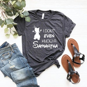 K&ouml;nnte beinhalten: Ein dunkelgraues T-Shirt mit einer wei&szlig;en Silhouette von Olaf aus Frozen und dem Text "Ich kenne nicht mal eine Samantha".