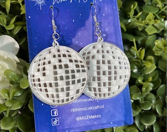 May include: Silver disco ball earrings with a grid pattern. The earrings are on a blue background with the text "Whimsical Craft Co." and social media handles.