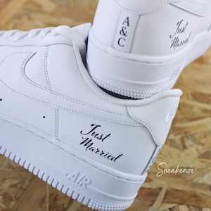 Peut inclure: Baskets blanches avec l'inscription "Just Married" en script noir sur le côté. Le talon affiche les initiales "A&C". Les chaussures ont un design classique avec le mot "AIR" sur la semelle.