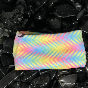 May include: A colorful headband with a chevron pattern in shades of pink, yellow, blue, and green.
