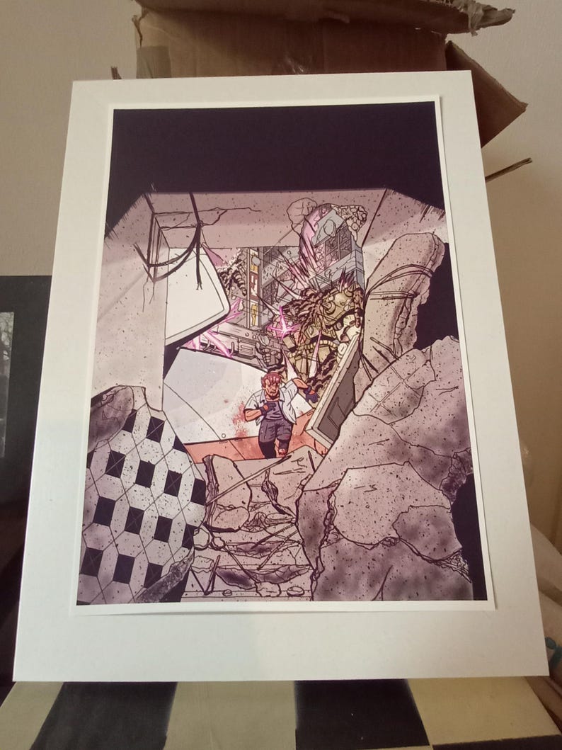May include: A framed comic book art print depicting a scene of destruction. The artwork features a figure in a white shirt and gray pants amidst rubble. The color palette includes shades of gray, pink, and black, with a white mat.