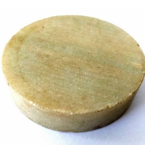 May include: A round, light green and beige stone grinding wheel.