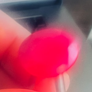 May include: A close-up of a bright pink, round, smooth object. The object is slightly out of focus.