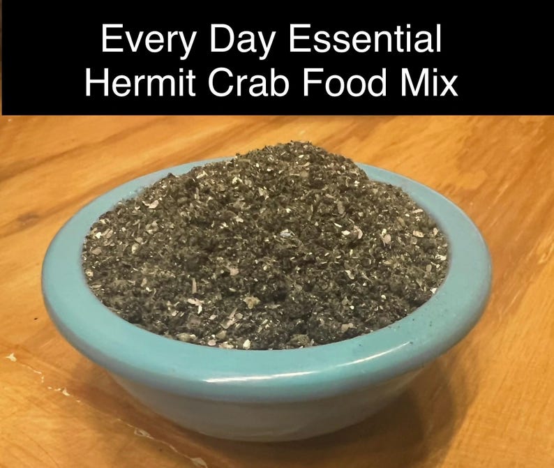 Puede incluir: Un taz&oacute;n azul lleno de una mezcla de comida gris oscuro y blanco etiquetada como "Every Day Essential Hermit Crab Food Mix".