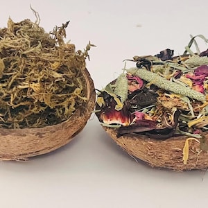 May include: Two halves of a coconut shell filled with natural materials. One half is packed with dried moss, the other with a mix of dried flowers, herbs, and petals. The shells are brown and the contents are various shades of green, brown, and red.