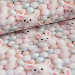 May include: A fabric pattern featuring a repeating design of plush white bunnies with pink-lined ears and black eyes, interspersed with pastel-colored egg-shaped elements. The background is a mix of fluffy white and pastel pink textures.