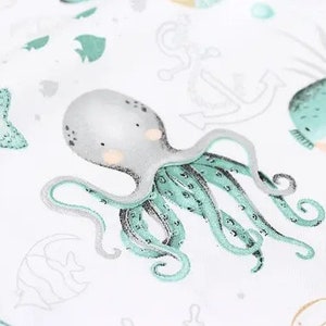 May include: White fabric with an aquatic theme featuring an octopus, starfish, and whale illustrations in shades of gray, teal, and beige. The octopus has teal tentacles and a gray head. Other sea creatures and nautical elements are also present.
