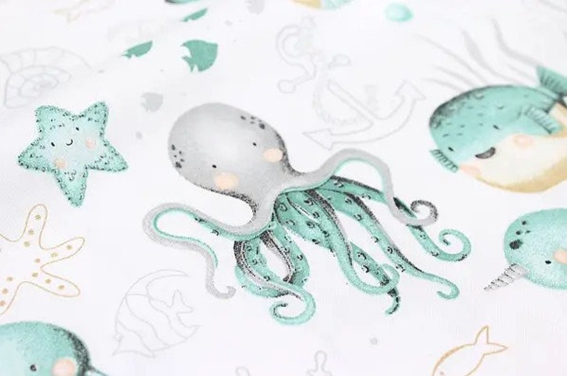 May include: White fabric with an aquatic theme featuring an octopus, starfish, and whale illustrations in shades of gray, teal, and beige. The octopus has teal tentacles and a gray head. Other sea creatures and nautical elements are also present.