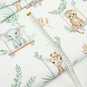 May include: White fabric with a repeating pattern of jungle animals on swings. The animals include an elephant, giraffe, and cheetah. The fabric is decorated with green leaves and brown branches.