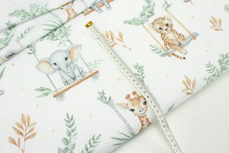 May include: White fabric with a repeating pattern of jungle animals on swings. The animals include an elephant, giraffe, and cheetah. The fabric is decorated with green leaves and brown branches.