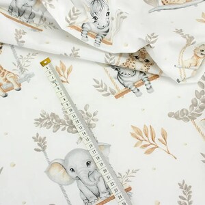May include: White fabric with a repeating pattern of various animals on swings. The animals include a giraffe, zebra, elephant, and leopard. The fabric has a watercolor-like design with brown, gray, and beige colors.