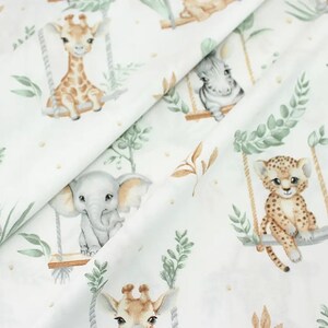 May include: White fabric with a repeating pattern of jungle animals on swings. The animals include a giraffe, elephant, leopard, and zebra. The fabric has a watercolor-like style with green leaves and brown branches.