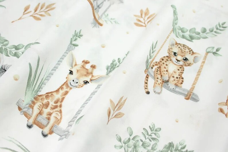 May include: White fabric with a repeating pattern of giraffes and leopards on swings. The animals are illustrated in a watercolor style with brown, tan, and green colors.