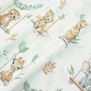 May include: White fabric with a repeating pattern of various animals on swings. The animals include a giraffe, a lion, a leopard, and an elephant. The animals are all in a cartoon style and are surrounded by green leaves and brown branches.
