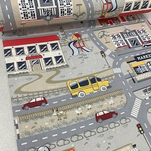 May include: A gray and beige fabric with a printed design of a city street scene. The scene includes a school building, a market, a playground, a yellow school bus, and red cars. The fabric has a textured surface.