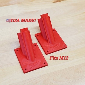May include: Two red plastic wall mounts for Milwaukee M12 tools. The mounts are labeled "M12 Milwaukee" and "Fits M12".
