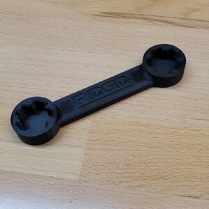 以下が含まれることがあります： 両端にソケットが2つ付いた黒いプラスチック製のレンチ。レンチには「RIGID」と表示されています。