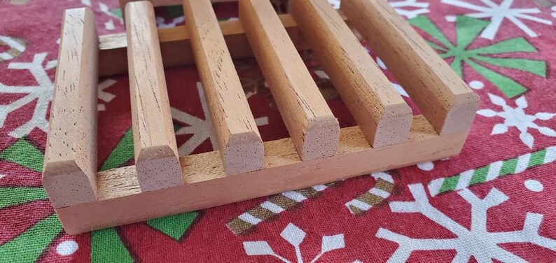 May include: A wooden soap dish with a grid pattern. The dish is made of light brown wood and has a natural finish.