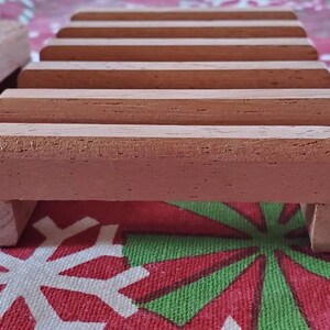 May include: A wooden soap dish with five slots for holding bars of soap. The dish is made of light brown wood and has a natural finish.