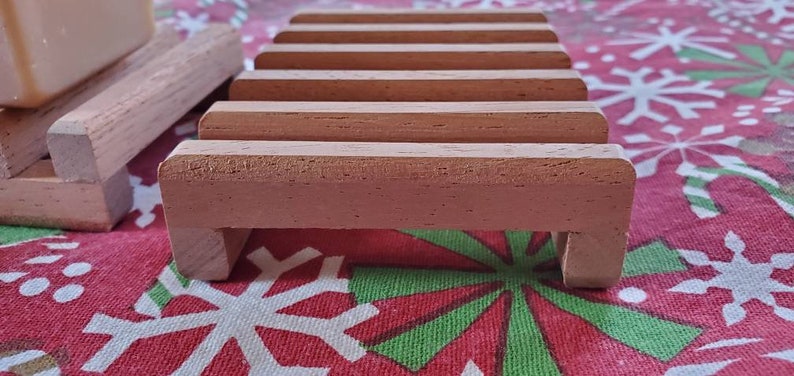 May include: A wooden soap dish with five slots for holding bars of soap. The dish is made of light brown wood and has a natural finish.