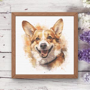 Op de afbeelding: Een vierkant ingelijst wandkunstwerk met een aquarel-stijl illustratie van een Corgi-hond met een beige en witte vacht, puntige oren en een open mond. Het kunstwerk zit in een eenvoudige bruine houten lijst met een zichtbare houtnerf.