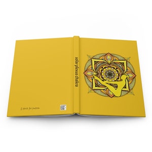 May include: A yellow journal with a mandala design on the cover. The mandala features a yellow, orange, and brown color scheme and depicts a person in a yoga pose. The text "solar plexus chakra" is printed on the spine of the journal.
