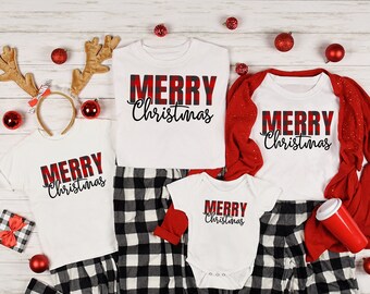 May include: A collection of matching Christmas pajamas and accessories. The white shirts and onesie feature "MERRY Christmas" in a red and black plaid design. Black and white plaid pajama pants, red ornaments, and reindeer antlers complete the festive ensemble.