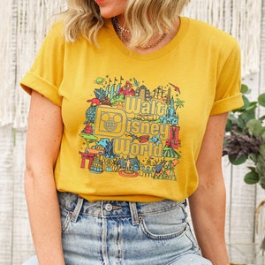 May include: A yellow t-shirt featuring a colourful graphic of Walt Disney World landmarks and the text "Walt Disney World".