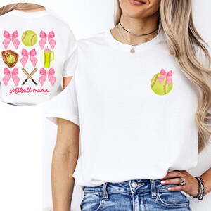 May include: White t-shirt with a pink softball and bow design. The back of the shirt has a pink bow, softball, and crossed bats design with the text "softball mama".