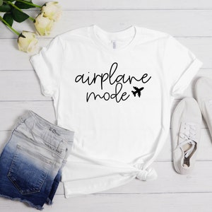 May include: White t-shirt with black text that says "airplane mode" and a small airplane graphic.