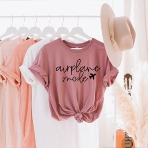 May include: A dusty rose t-shirt with the text "airplane mode" and a small airplane graphic printed in black.