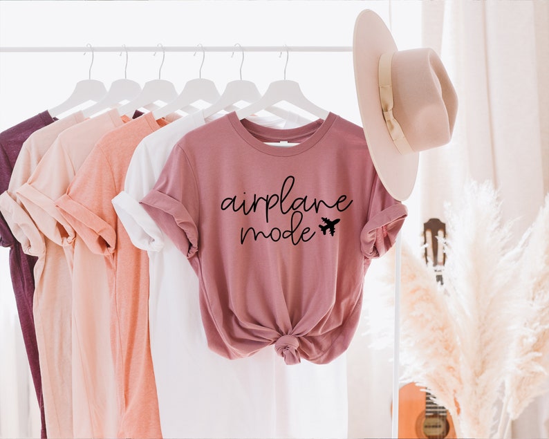 May include: A dusty rose t-shirt with the text "airplane mode" and a small airplane graphic printed in black.