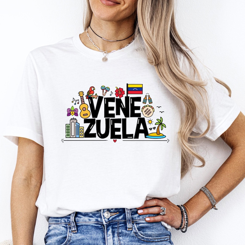 May include: White t-shirt with a colorful graphic design that says "VENEZUELA". The graphic includes a guitar, a parrot, a flag, and other icons.