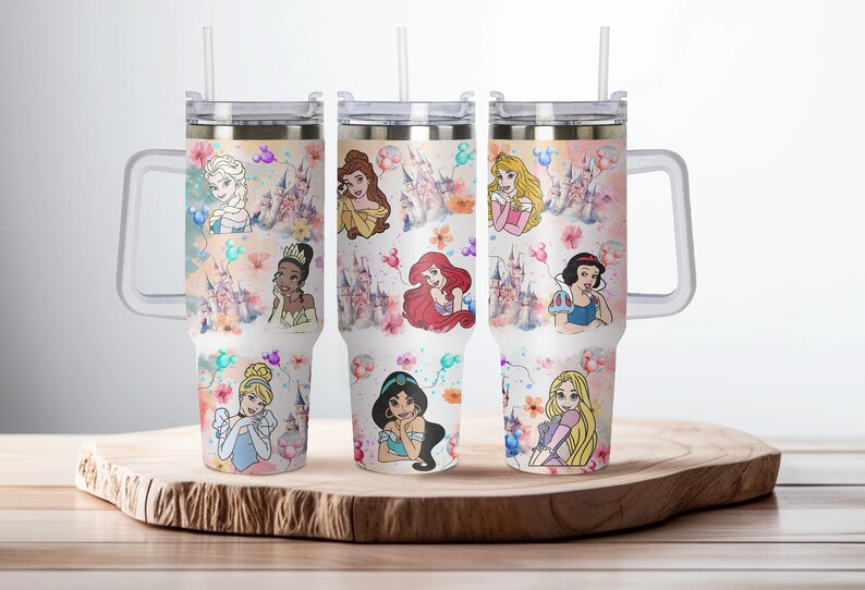 May include: Set of three stainless steel tumblers with a white background and colorful images of Disney princesses. The tumblers have a clear lid and a handle.