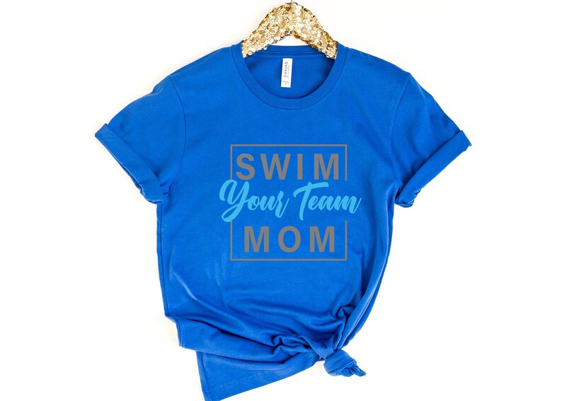 K&ouml;nnte beinhalten: Ein k&ouml;nigsblaues T-Shirt mit dem Text "Swim Your Team Mom" in einem grauen Kasten mit blauen Buchstaben.