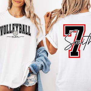 May include: Two white t-shirts, one with the text "VOLLEYBALL mom" and a volleyball graphic, and the other with a black number "7" and the text "Smith" in a red and black frame.