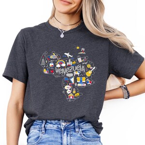 Może przedstawiać: Szary t-shirt z nadrukiem przedstawiającym mapę Wenezueli z kolorowymi ikonami i napisem "Venezuela".