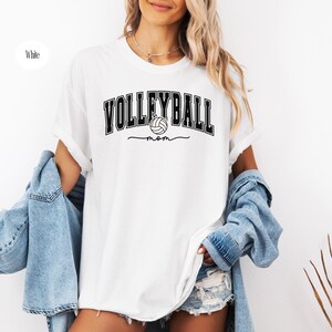 May include: White t-shirt with black text that reads "Volleyball mom" and a volleyball graphic.